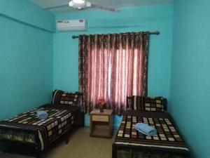 two beds in a room with blue walls and a window at Cliff Hostel in Amman