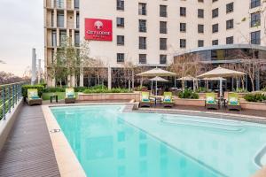 City Lodge Hotel Hatfield, Pretoria في بريتوريا: مسبح فيه كراسي ومظلات امام الفندق