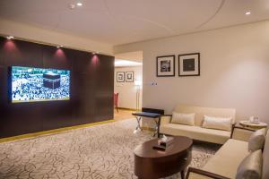 a living room with a couch and a tv on a wall at Al Aryam Serviced Aparthotel in Buraydah