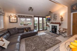 a living room with a leather couch and a fireplace at Mistletoe One Luxury Lodge with Hot Tub Windermere in Windermere
