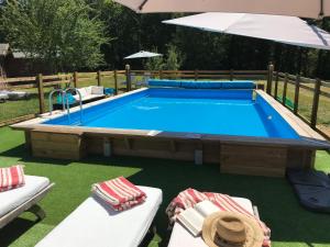 a swimming pool in a yard with two chairs and an umbrella at La Rame in Chalais