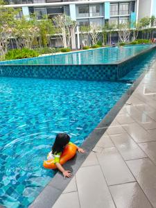 una niña en una balsa en una piscina en Homestay KLIA Core Soho Suites, en Sepang