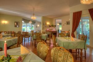 un restaurante con mesas verdes, sillas y mesa de comedor en Hotel Brigitte en Bad Krozingen