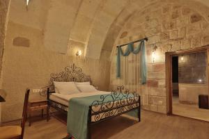 - une chambre avec un lit dans un mur en pierre dans l'établissement Jacob's Cave Suites - Cappadocia, à Gorëme