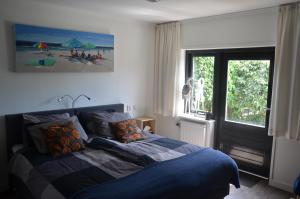 una camera da letto con un letto con una coperta blu e una finestra di B&B Onder de Molen a Burgh Haamstede