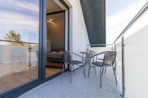 a glass balcony with a table and chairs on it at Verde House in Karwia