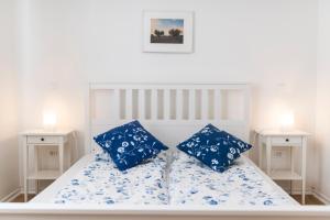 a white bed with blue pillows in a bedroom at Pribetic Apartments in Poreč