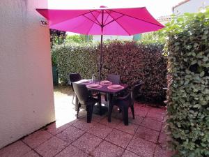 une table violette avec des chaises et un parasol dans l'établissement Logement 106 2-4 Personnes 500 m plage classé 2 Etoiles, à Dolus-d'Oléron