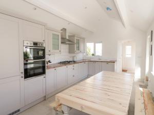 une cuisine avec des placards blancs et une table en bois dans l'établissement Y Gogarth, à Benllech