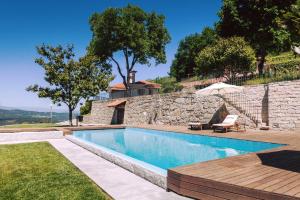 einen Pool neben einer Steinmauer mit einem Sonnenschirm in der Unterkunft Quinta do Fontelo in Vouzela