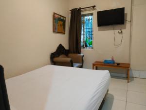 um quarto com uma cama, uma televisão e uma janela em Pemda 22 Mansion Mitra RedDoorz em Bogor