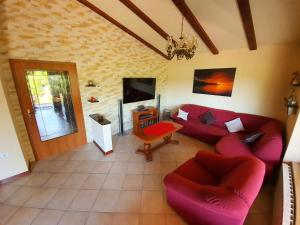 a living room with red couches and a tv at Tunia in Strunjan