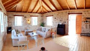 a living room with white furniture and stone walls at The House. Light & Stone. in Lixouri