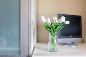 a vase of white tulips in front of a television at Lets Holidays garden house in front of the beach in Tossa de Mar