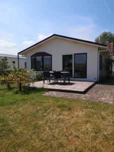 ein Haus mit einer Terrasse und einem Tisch davor in der Unterkunft Chalet Stalland in Sint-Annaland