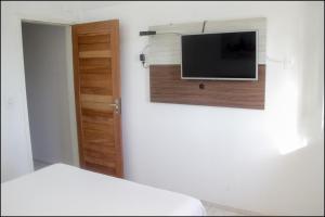 1 dormitorio con 1 cama y TV en la pared en Pousada Amor a Mar, en Icapuí