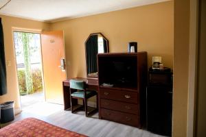 ein Schlafzimmer mit einer Kommode mit einem TV und einem Spiegel in der Unterkunft Kings Inn Hot Springs in Hot Springs