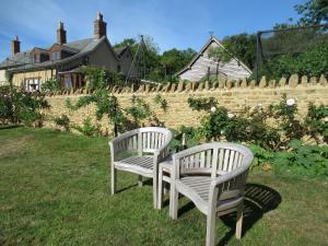 two white chairs sitting in the grass near a fence at Wooden Cabbage Barn in Dorchester