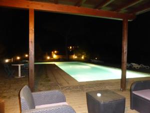 a swimming pool at night with chairs and a table at Country House La Casa Paterna in Monte Santa Maria Tiberina