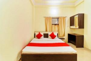 Hotel Station View Mughalsarai by ShriGo Hotels في Mughal Sarāi: غرفة نوم بسرير ومخدات حمراء