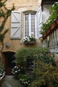 a building with a window with flowers and plants at Les Chambres de L'Horloge in Lectoure