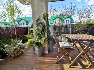 a patio with a wooden table and potted plants at Apartament Green Plant - 2 oddzielne sypialnie, taras 30m2 i garaż podziemny in Kielce