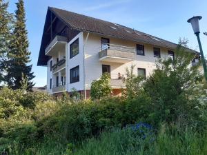 a white building with a balcony on a hill at Wohnen wie bei Freunden in Braunlage