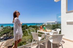 a woman standing on a balcony overlooking a beach at Houm Plaza Son Rigo in Playa de Palma