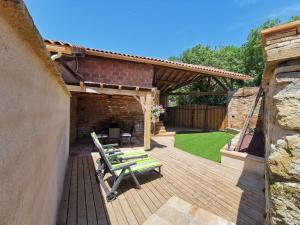 a patio with two green benches on a wooden deck at Gîte le jardin secret et Gîte au temps suspendu in Montpézat