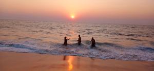 een groep mensen die in het water op het strand staan bij Alleppey - The Beach Home in Alleppey
