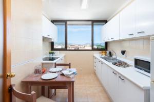 cocina con armarios blancos y mesa de madera en Apartamentos Carlos V, en Alcudia