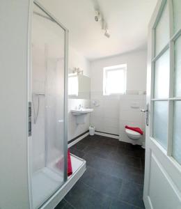 a bathroom with a shower and a toilet and a sink at Hotel-Pension Haus Hubertus in Borkum