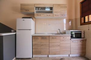 La cuisine est équipée d'un réfrigérateur blanc et d'un four micro-ondes. dans l'établissement AK VILLAGE ROOMS, à Drepano