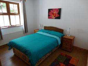 a bedroom with a bed with a blue comforter at The River House in Releagh