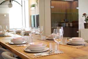 a wooden table with plates and glasses on it at Exclusivo ático en el centro de Castro Urdiales in Castro-Urdiales