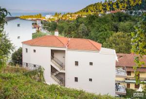 a white building with an orange roof on a hill at Marina's Elegance in Kriopigi