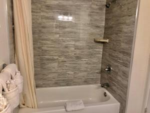La salle de bains est pourvue d'une baignoire blanche et d'une douche. dans l'établissement Pelican Inn, à Monterey
