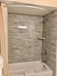 La salle de bains est pourvue d'une baignoire blanche et d'un mur en carrelage. dans l'établissement Pelican Inn, à Monterey