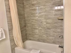 La salle de bains est pourvue d'une baignoire blanche et d'une douche. dans l'établissement Pelican Inn, à Monterey