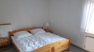 フェーマルンにあるFerienwohnung Erdgeschossの白いシーツが敷かれた木製ベッドのある寝室
