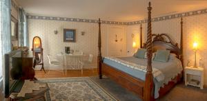 ein Schlafzimmer mit einem Himmelbett und einem Tisch in der Unterkunft The Bridges Inn at Whitcomb House B&B in Swanzey