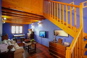 sala de estar con paredes azules y escalera de madera en Vallespin Suite en Avila