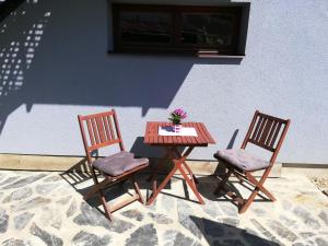 2 sillas y una mesa de madera con un jarrón de flores en Apartmán u Kartouzky en Dolany