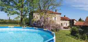 a large swimming pool in front of a house at Wisteria House in Chanteloup