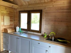 a kitchen with white cabinets and a window in a log cabin at Zielone Domki in Wiele