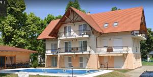 une maison avec un toit orange et une piscine dans l'établissement Promenade Apartman, à Balatonlelle