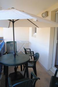 een tafel en stoelen met een parasol op een balkon bij Agréable T2 balcon et piscine dans résidence bord de mer in Lacanau-Océan