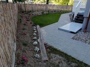 einen Hinterhof mit einem Zaun und einem Garten mit Blumen in der Unterkunft Dworek Nadmorski in Władysławowo