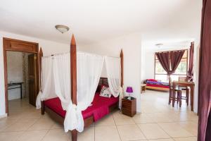 1 dormitorio con 1 cama con dosel en Punta Duarte Garden Inn en Los Duarte