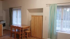 Il comprend une cuisine avec une table, une armoire en bois et des fenêtres. dans l'établissement Larida Vendégház, à Sarud